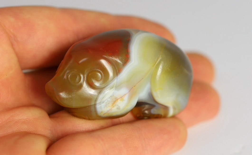 A Chinese banded agate figure of a recumbent pig, 18th/19th century, 5.4cm long, wood stand